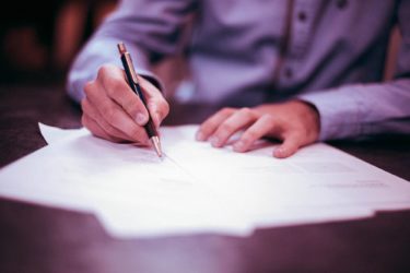 Photo of man signing a legal document. (photo: unsplash)