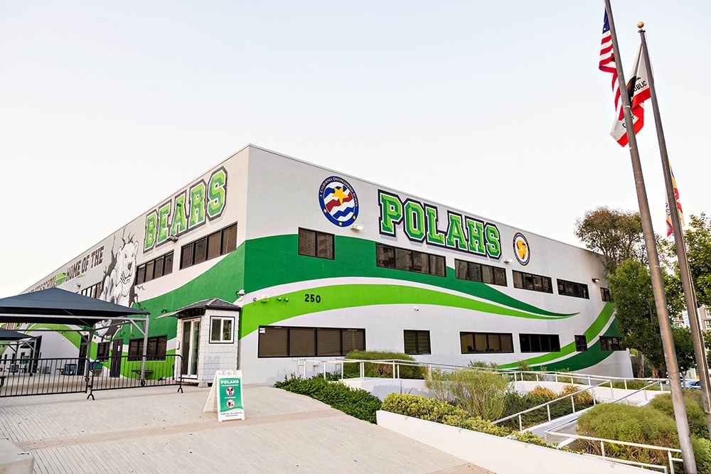 Port of Los Angeles High School building with green wavy stripes painted on the walls and 'POLAHS' written in green block letters.